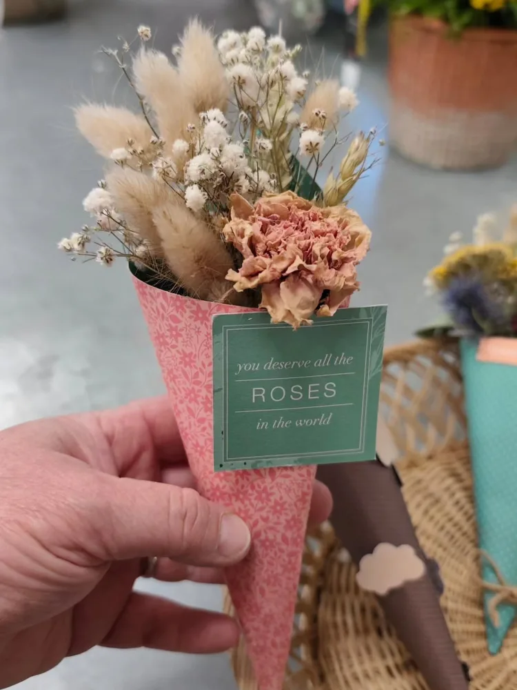 Cornet de fleurs séchées aux tons beige et vieux rose, avec queues de lapin et gypsophile, tenu à la main